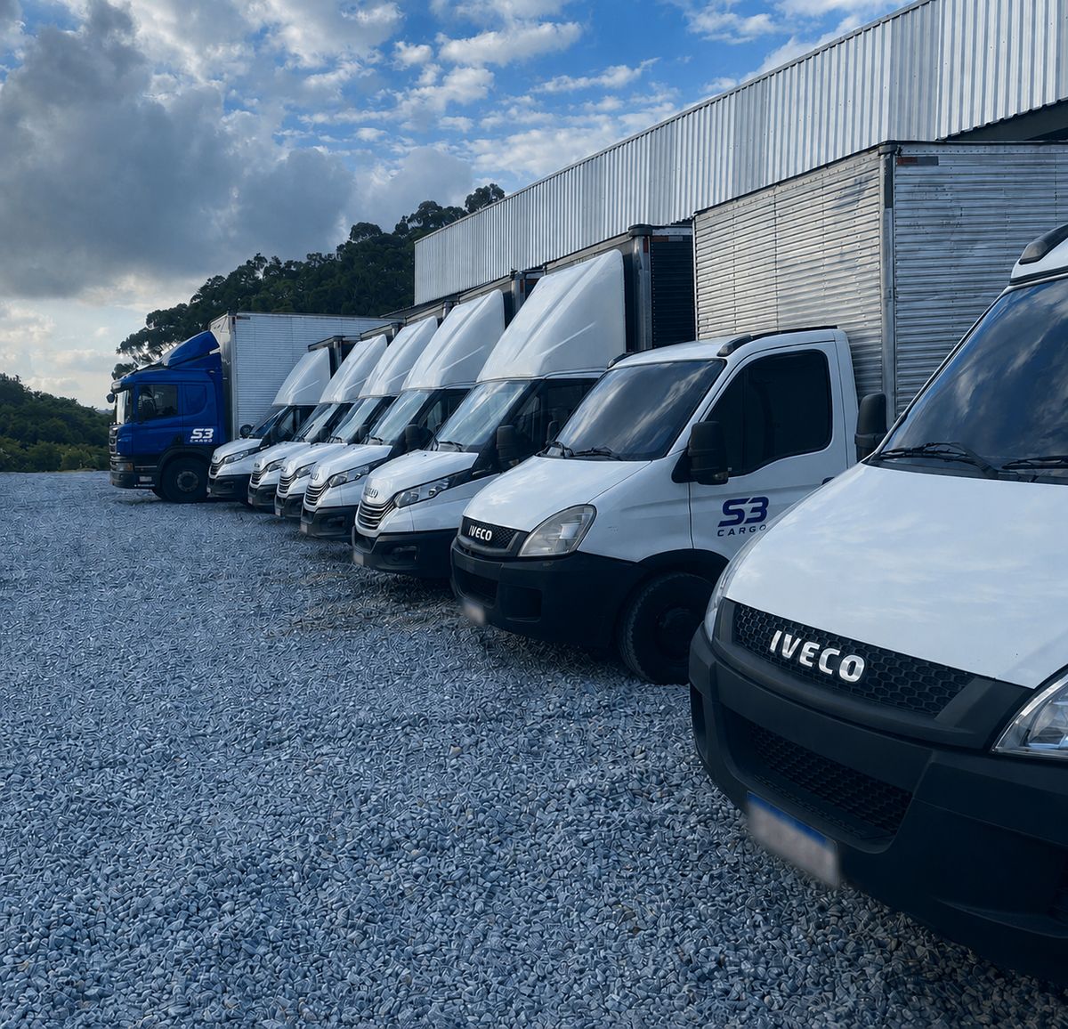 Fileira de vans e caminhões da frota S3 Cargo estacionados junto ao armazém